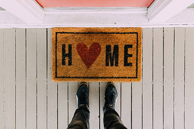 Person at door with feet in front of Home door mat.