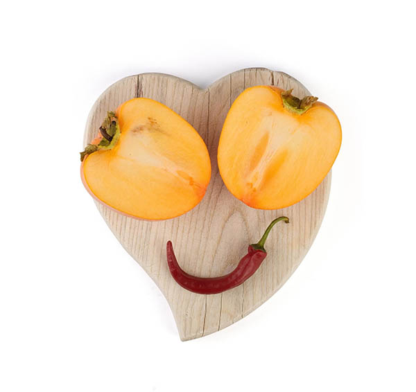 Heart shape cutting board with two peppers for the nose and a chili pepper for the mouth