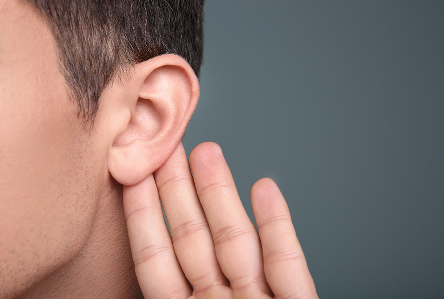 Person with open palm behind earlobe