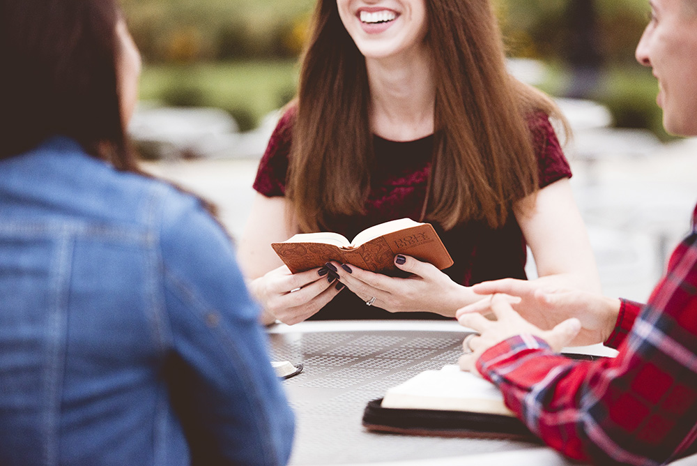 Close up shot of females sitting around a table in a bible study group